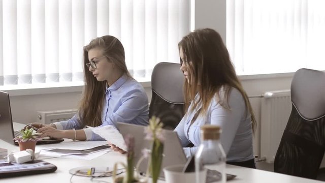 Two girls cheking their documents at office. One of them have found a huge mistake.