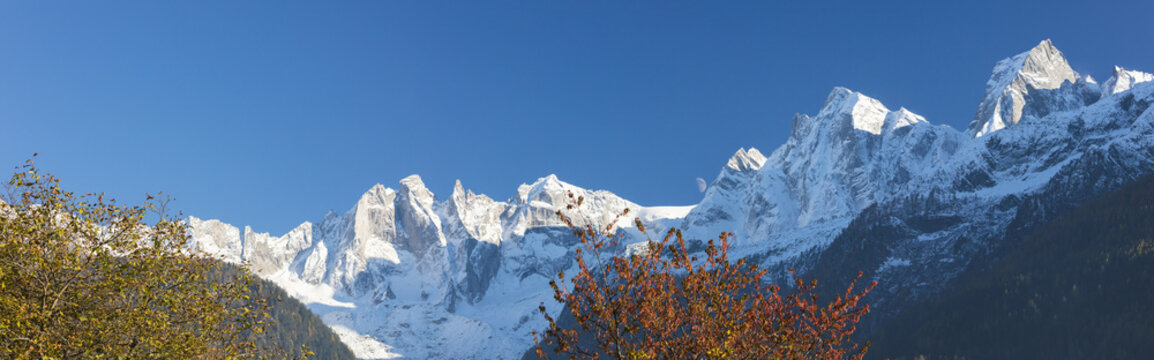 Panorama of the snowy peaks framed by colorful trees, Soglio, Bregaglia Valley, Canton of Graubunden
