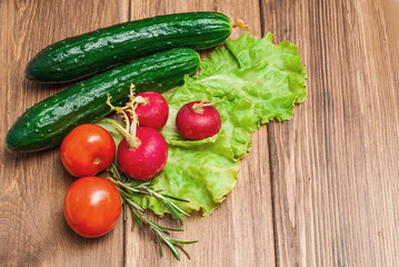 Fresh vegetables, cucumbers, tomatoes and radish on a wooden table