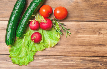 Fresh vegetables, cucumbers, tomatoes and radish on a wooden table