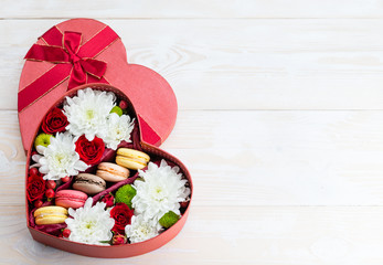 Box of flowers and macaroons heart on a wooden table. Copy space