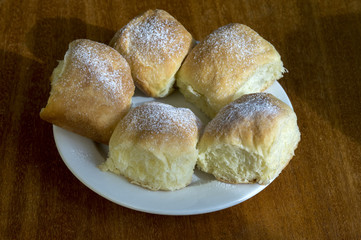 Five homemade traditional Czech buns stuffed with plum jam, raisins and cottage cheese on white plate on wooden table