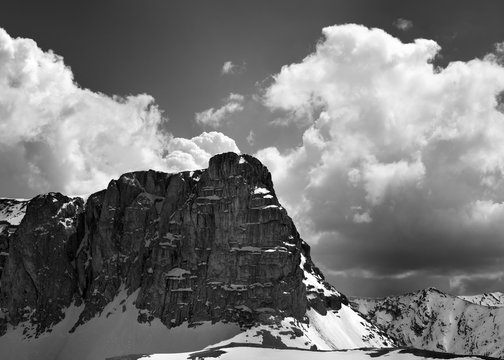 Fototapeta Black and white view on snowy rocks and sky with clouds in nice spring day