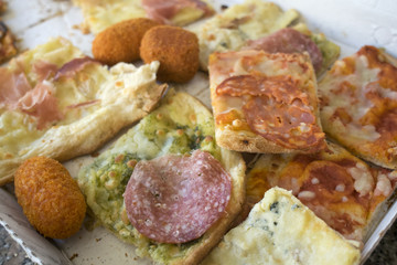 variety of types of pizza cut in pieces and arancine