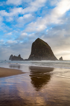 Haystack Rock reflected on the shoreline at Cannon Beach on the Pacific Northwest coast, Oregon