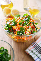 Thai salad from noodles raw carrots and cucumber with chickpeas, cilantro and sesame in sweet and sour sauce in glassware on a wooden table. Selective focus.