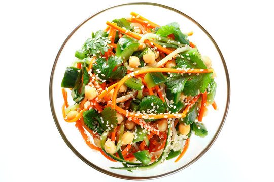 Thai salad from noodles raw carrots and cucumber with chickpeas, cilantro and sesame in sweet and sour sauce. Isolated on white, top view.
