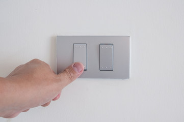Unidentified man hand with finger on light switch turn on turn off  lights.  Save the earth concept.