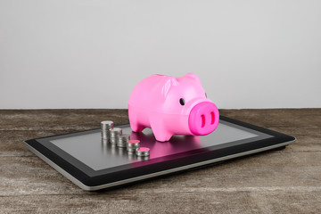 Piggybank and row of coin money on tablet