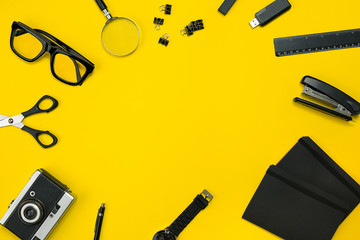 Black objects from the office on a yellow background. Work and creativity. Top view.