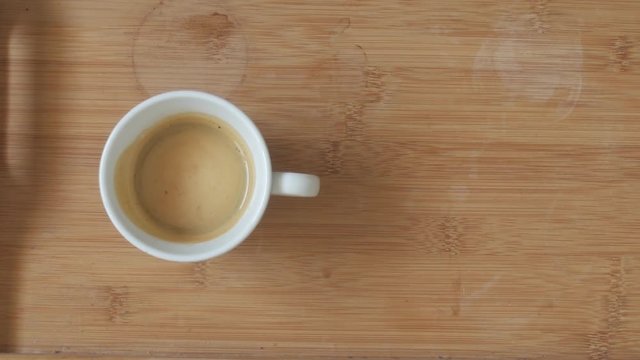 Putting milk in cup of coffee top-view