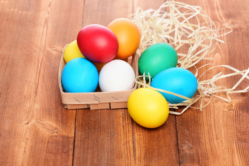 easter colorful eggs in wooden basket with straw nest