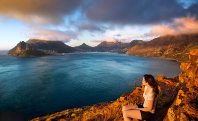 Young tourist woman looks at the sunset from Chapman's Peak Drive in Cape Town