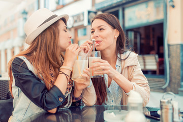 Two beautiful young girls sitting in a cafe