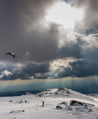 Snowkite on a mountain top under storm clouds and the rays of the setting sun