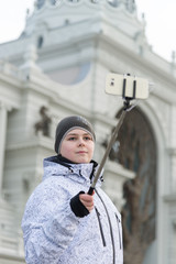 The boy makes selfie on phone with selfie stick on background of sights