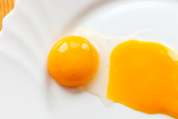 Closeup of broken eggs in a white bowl.