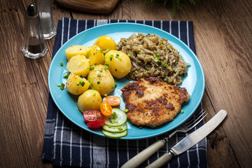 Fried pork chop, baked potatoes and fried young cabbage.