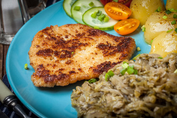 Fried pork chop, baked potatoes and fried young cabbage.