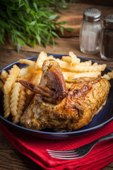 Roasted chicken with french fries on a plate.