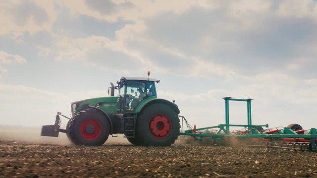 Tracking shot: tractor Plows the land in the field. Spring field works. Beautiful sunny day in good weather. Low angle 3-axis stabilized video
