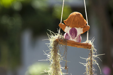 Clay doll on swing in garden.