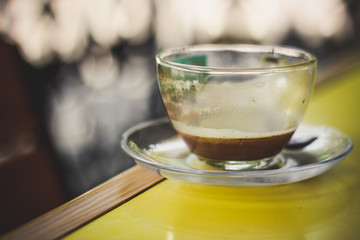 The rest of the drink in a transparent cup on the table (coffee)