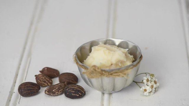 Hand picking up some she butter froma bowl. She nuts on the table