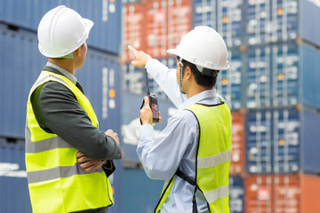 Asian Container inspector working in yard with communication device walkie talkie communicate report number checking