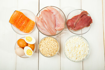 Proteins, fish, cheese, eggs, meat and chicken on a white wooden background - 144097794