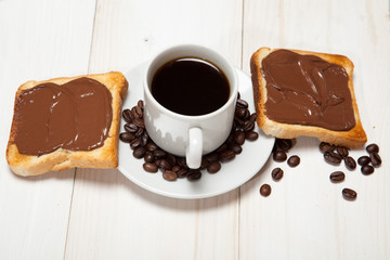 cup of coffee and toast with chocolate on a white wooden table