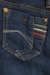 Fototapeta premium Texture fragment of denim with bright seams of thin fabric and a large pocket. The background image on the production of rigid denim clothing