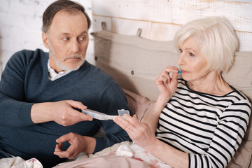 Obraz na płótnie Canvas Senior lady taking pills from her husband