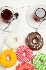 Two cups of tea and donuts on a white wooden table