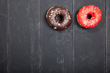 Colorful donuts on a black wooden background