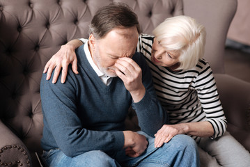 Elderly woman calming down her depressed husband.
