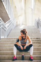 Fototapeta na wymiar Sports woman sitting on the stairs and relaxing 