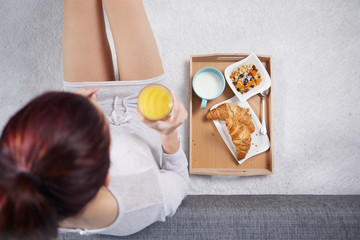 The girl in the morning eats a croissant and drink  juice. top view