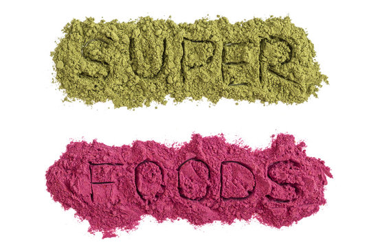 Superfoods word with green and pink powders isolated on white. Healthy food supplements, detox concept. Flat lay 