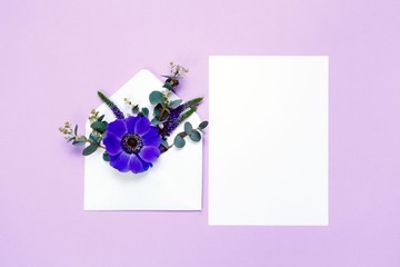 Colorful spring flowers in envelope and white sheet on violet background.