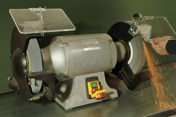 Manual sharpening of a tool on grinding machine with sparks close up