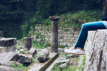 Girl is sitting on remains of a Doric temple, Mon Repos park, Corfu Town, Greece