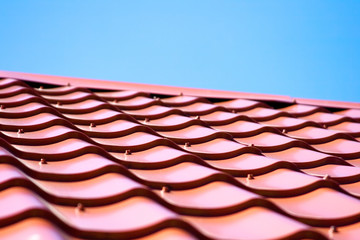 Red roof of metal roofing on the sky background