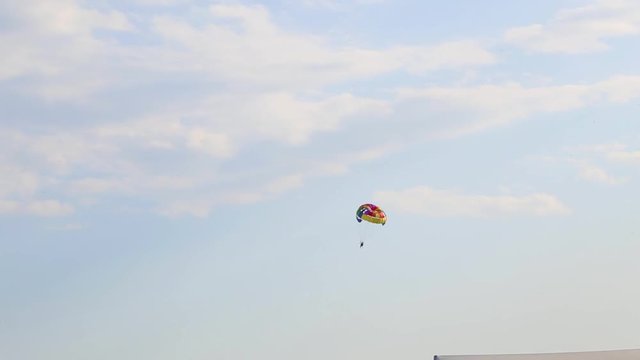 People flying with parachute in blue sky. Parasailing. Real time full hd video footage.
