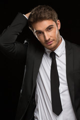 Sexy young suited man posing on black background