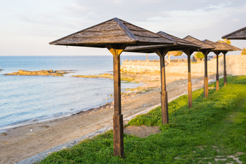 Decorative umbrellas made of palm branches on the background of the beach
