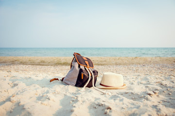 Vintage bag and straw hat lying on the beach on a background of the sea