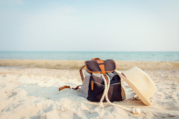 Vintage bag and straw hat lying on the beach on a background of the sea