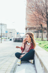 Fototapeta premium YOung woman sitting in the city talking smart phoe - communication, conversation, technology concept