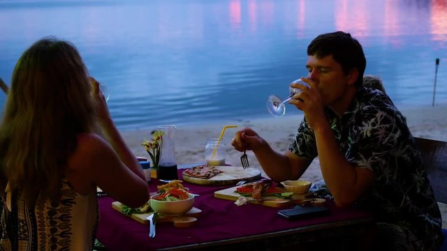 The family is dining in the restaurant on the beach.